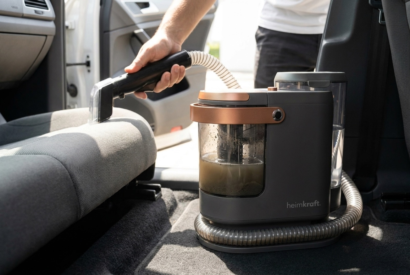 Der heimkraft DeepClean S15 reinigt einen Autositz, der transparente Tank zeigt das aufgesaugte Schmutzwasser